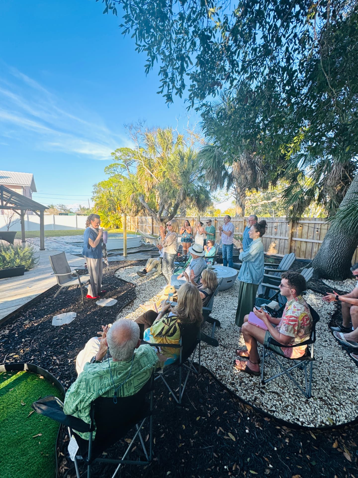 Backyard audience applauding an outdoor reading under the trees
